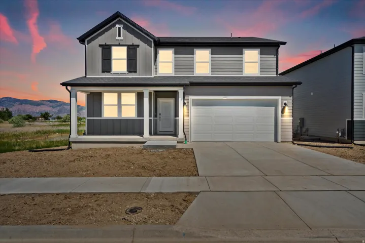 Two-story residence featuring a covered front porch, attached two-car garage, and a concrete driveway