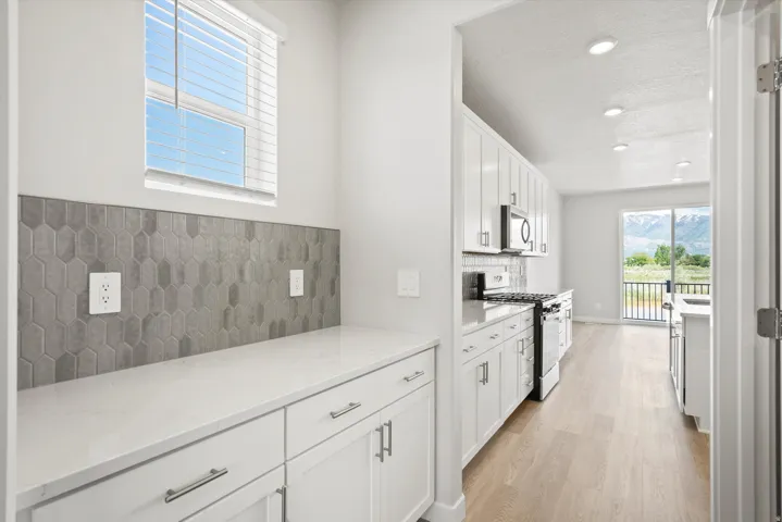 **DISCLAIMER** Some upgrades are not photographed. White cabinetry with polished hardware, light-toned wood-finish flooring, recessed lighting, and a neutral tile backsplash