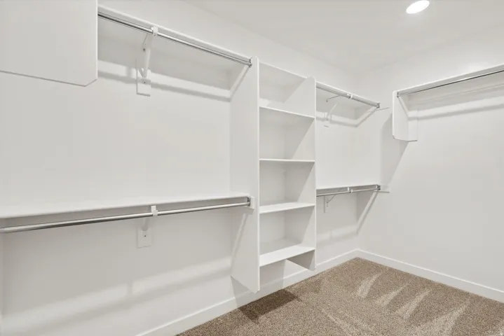 Walk-in closet with integrated shelving, multiple hanging rods, and recessed lighting