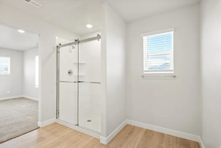 Shower enclosure with sliding glass doors, chrome fixtures, and built-in shelving