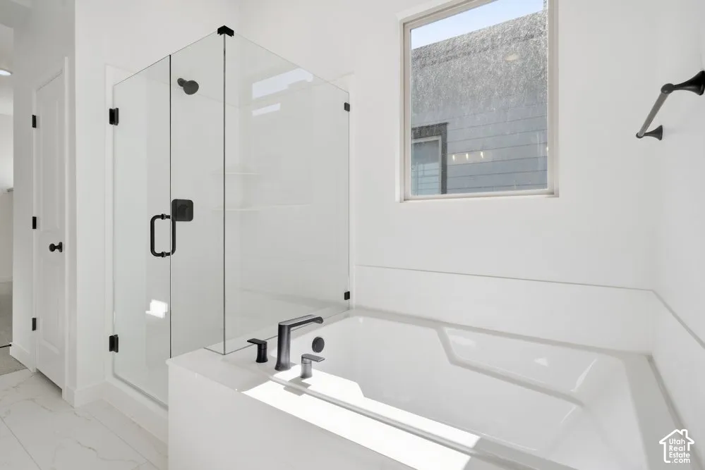 Walk-in glass-enclosed shower, soaking tub, matte black plumbing fixtures, and tile flooring