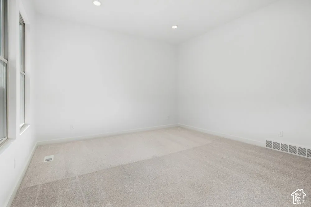 Neutral-toned carpeting, recessed ceiling lighting, and dual vertical windows