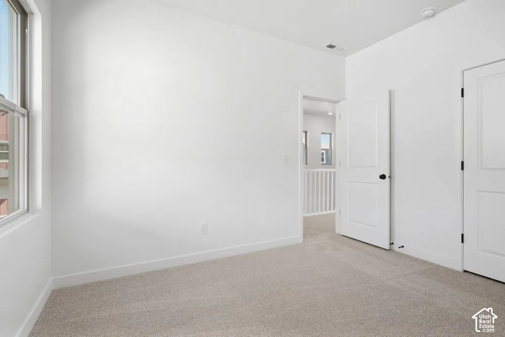 Neutral interior space featuring wall-to-wall carpeting, white walls, and multi-panel interior doors with matte black hardware