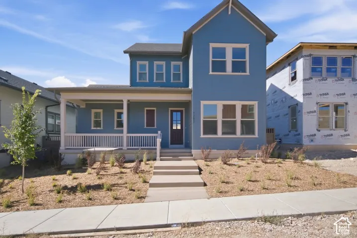 Two-story exterior featuring blue siding, a covered front porch with white railing, and multi-light windows