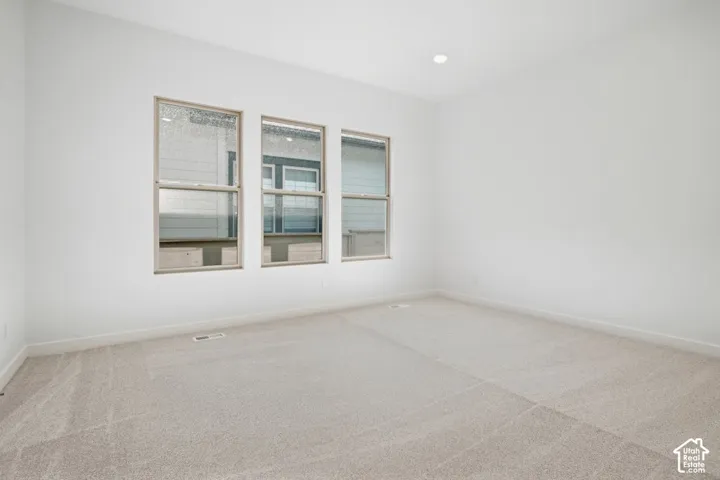 Neutral-toned carpeting, high ceilings with recessed lighting, and a triple-window configuration with frames