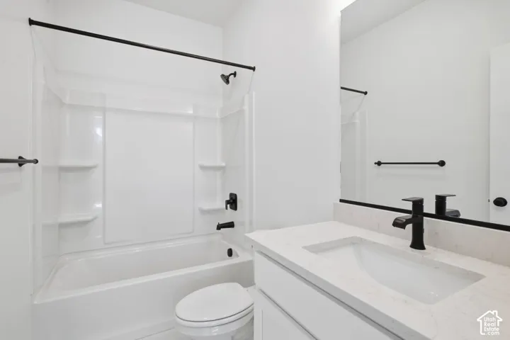 Bathroom featuring a vanity with a white composite countertop, undermount sink, matte black faucet, and a combined tub and shower surround with matte black fixtures