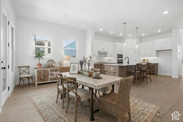 Open-concept kitchen featuring two-toned cabinetry, a large central island, recessed lighting, glass pendant fixtures, and wood-finish flooring