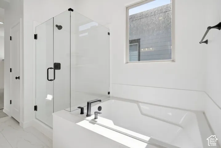 Walk-in glass-enclosed shower, soaking tub, matte black plumbing fixtures, and tile flooring