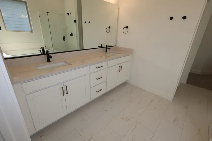 Double vanity with integrated sinks, light-colored countertop, and matte black fixtures
