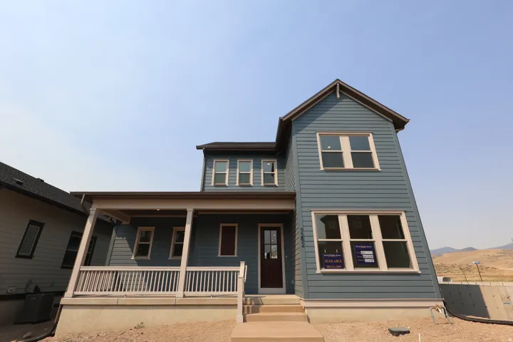 Two-story residential structure with blue horizontal siding, a covered front porch, white railings, and a dark front door