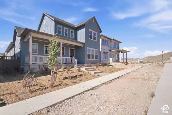 Two-story exterior featuring blue siding, a covered front porch with white railing, concrete steps, and mountain backdrop
