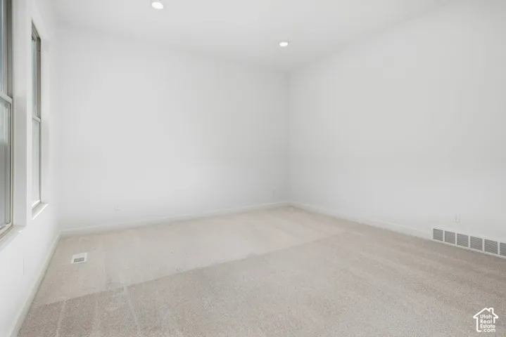 Neutral-toned carpeting, recessed ceiling lighting, and dual vertical windows