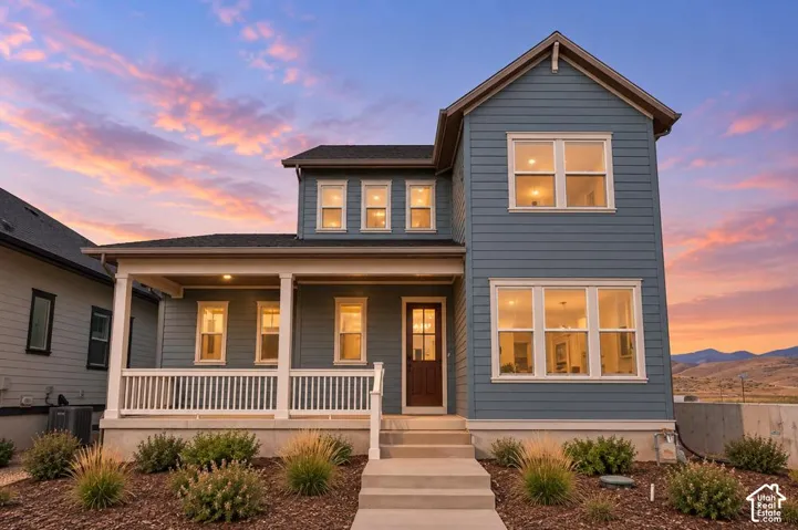 Two-story residence featuring horizontal siding, a covered front porch with white railing, and multi-pane windows