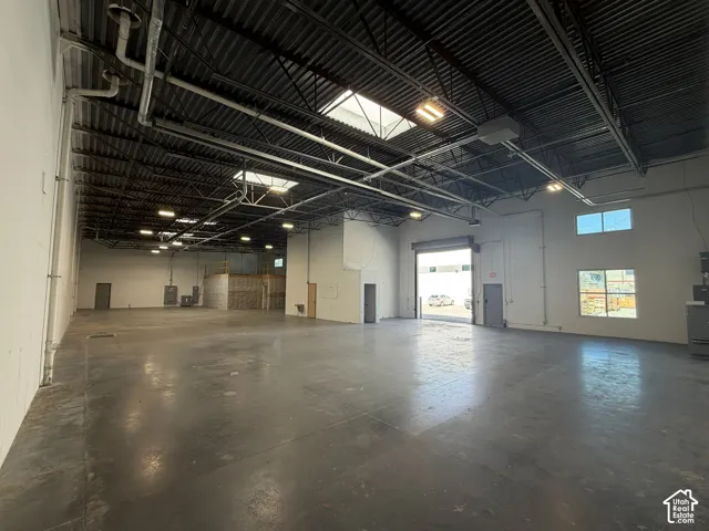 Expansive concrete floor space with high industrial ceilings, overhead lighting, and multiple skylights