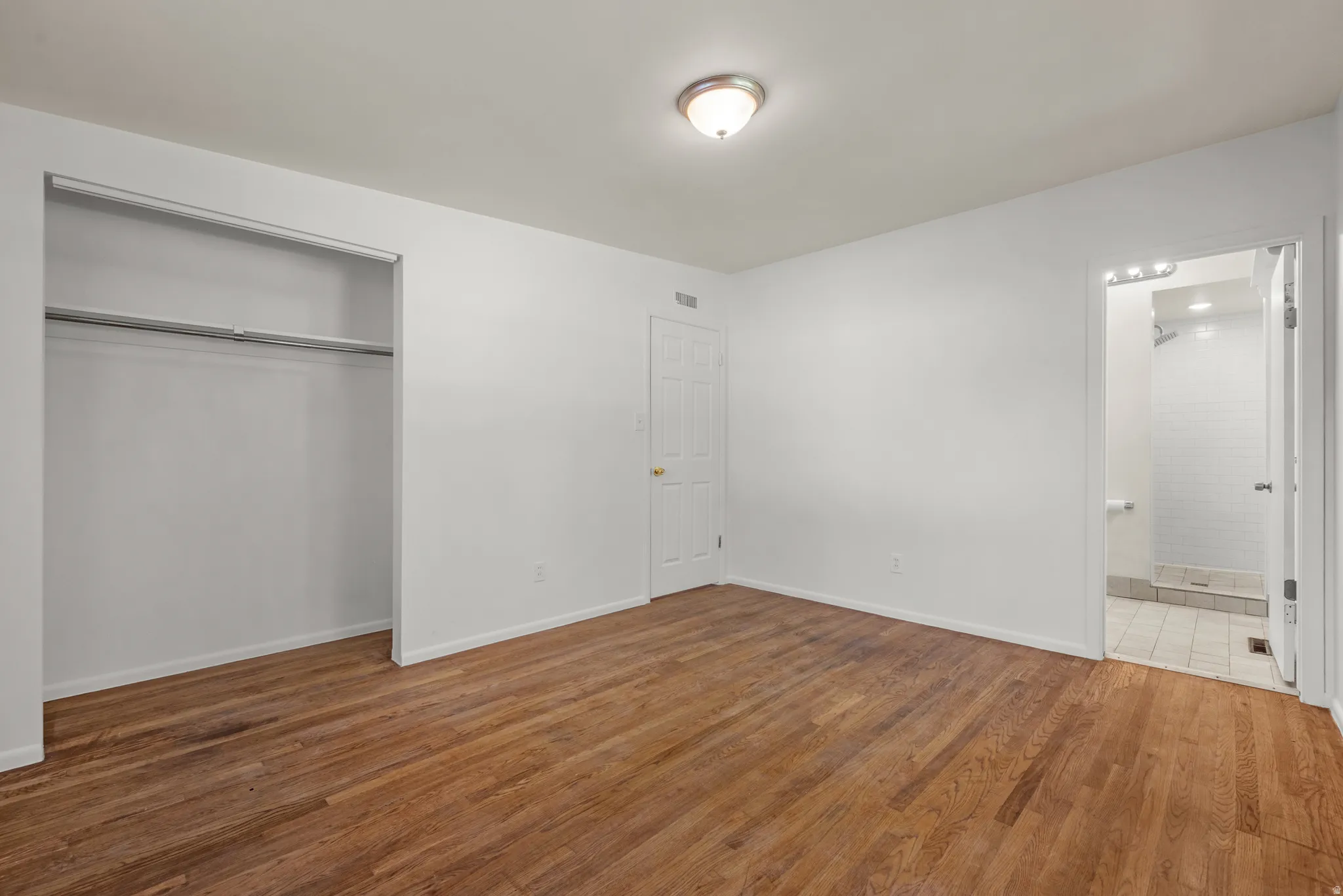 Primary Bedroom featuring hardwood flooring, white painted walls, and two large windows