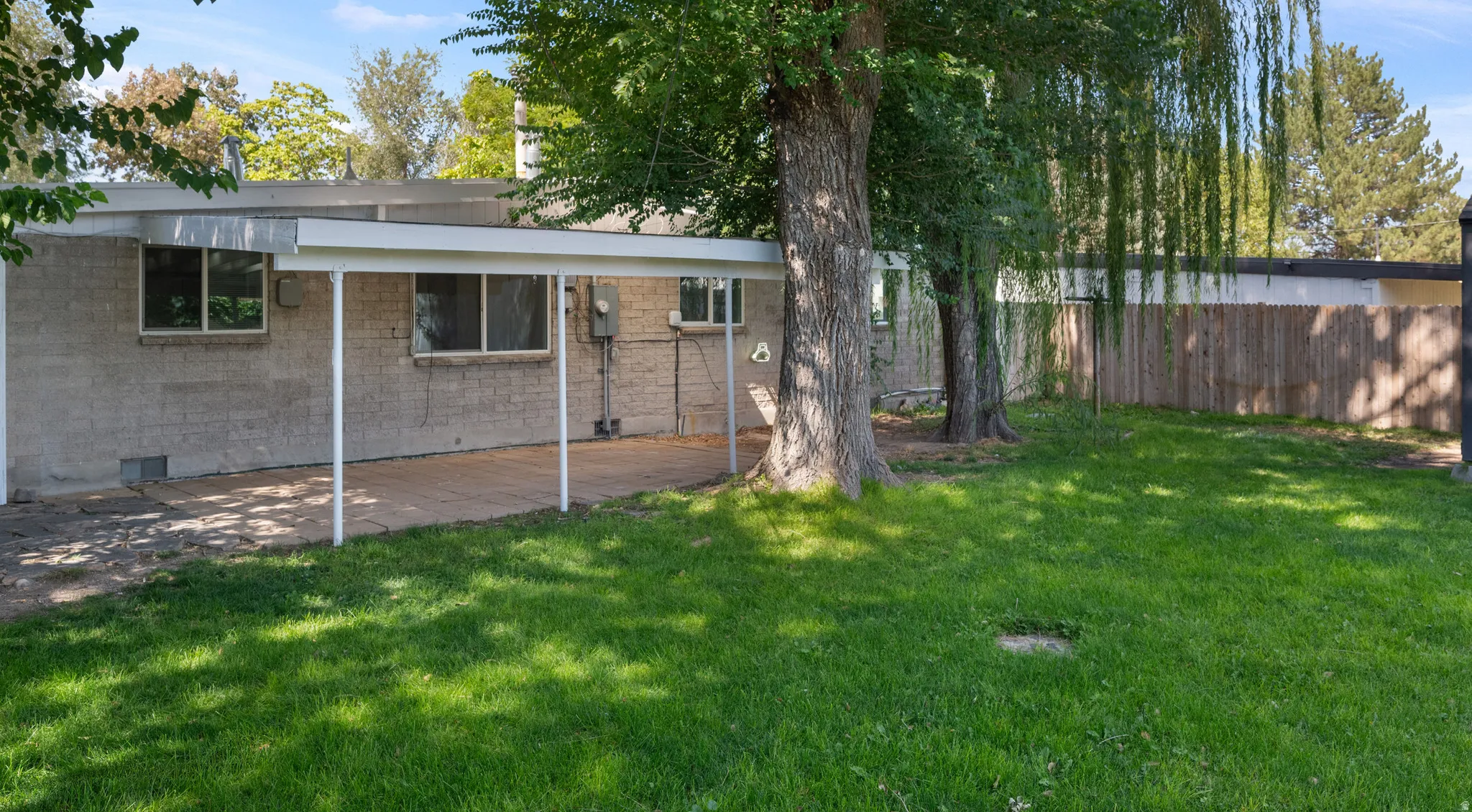 Rear exterior featuring a covered patio and mature trees