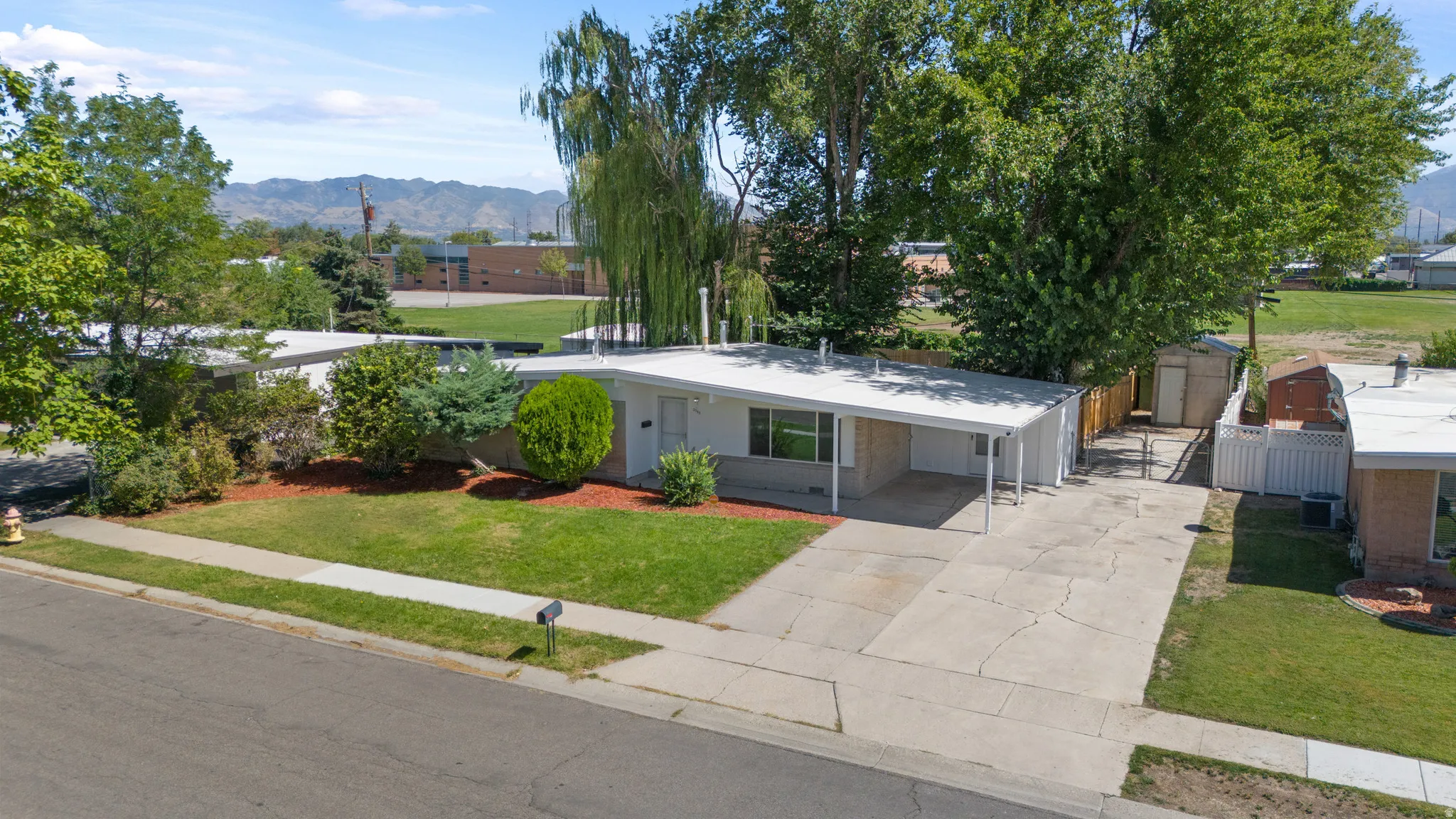 Single-story residence with a covered carport, concrete driveway, RV Parking and established landscaping