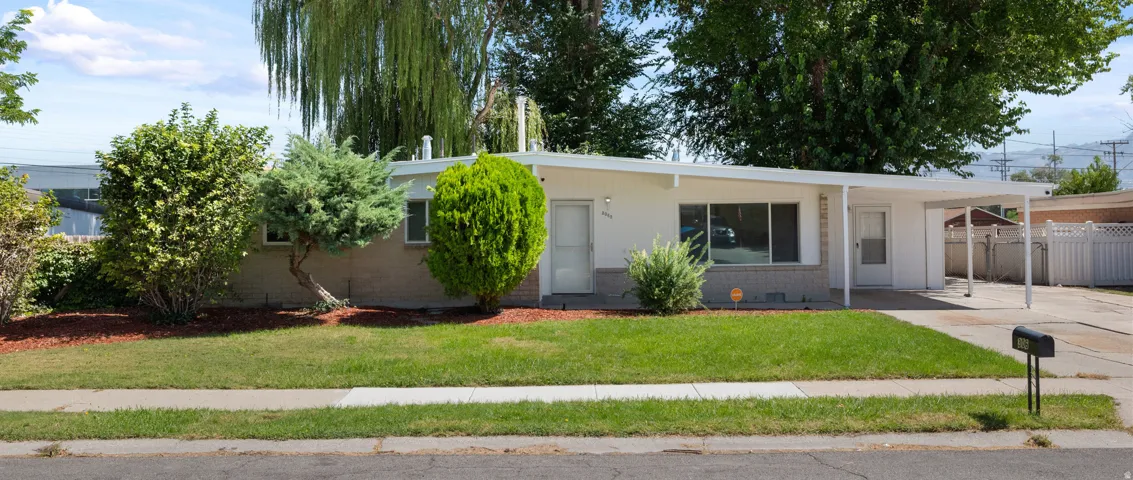 Single-story residence featuring a carport, front lawn, and mature landscaping