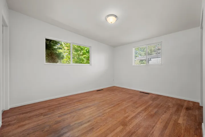 Primary Bedroom featuring hardwood flooring, white painted walls, and two large windows