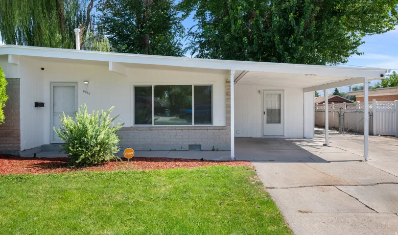Single-story exterior with a carport, front lawn, and mature landscaping