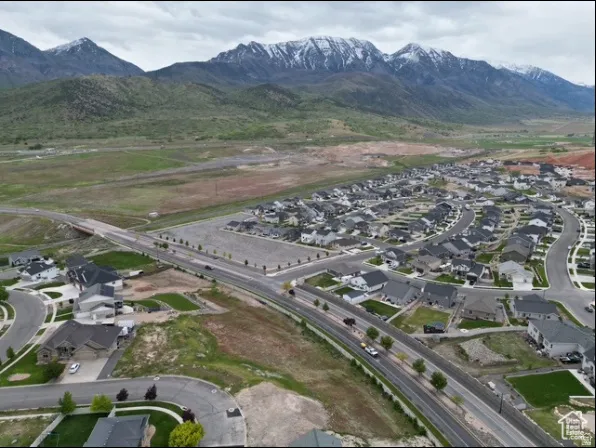 Residential development with established homes, paved roads, and mature trees, set against a backdrop of snow-capped mountains and expansive green space