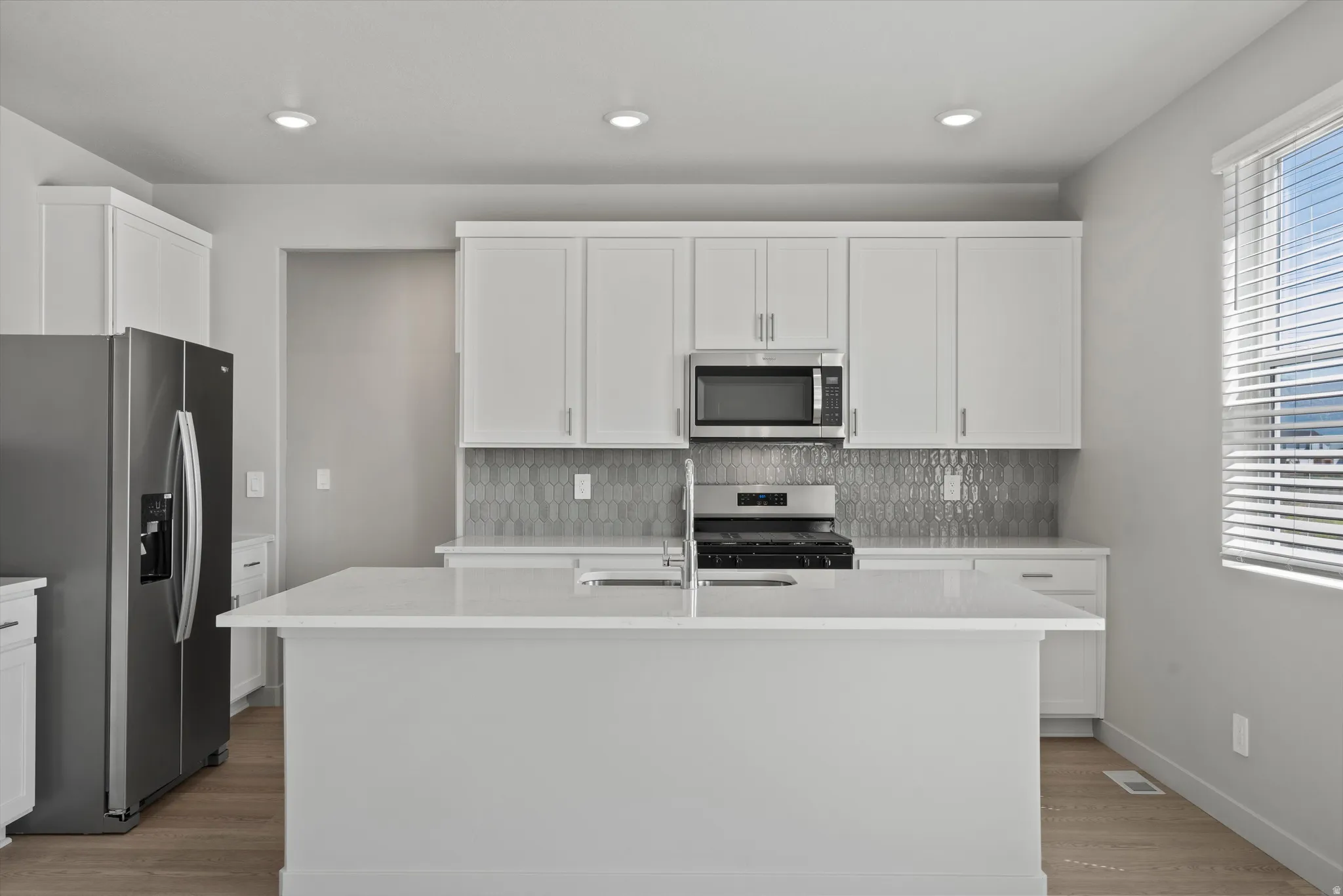 **DISCLIAMER** Some upgrades not photographed. Modern kitchen featuring a central island with countertop, stainless steel appliances, white cabinetry, and recessed lighting