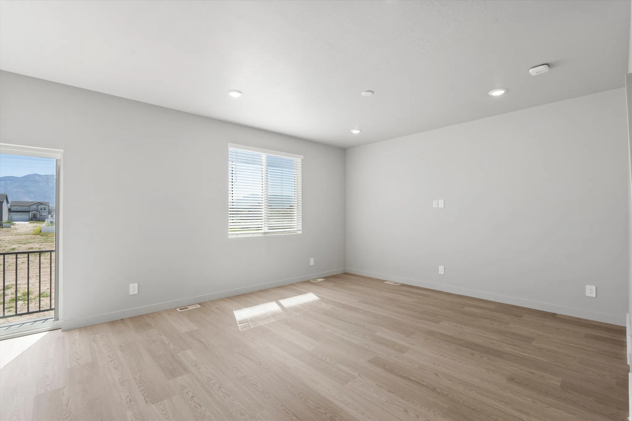 **DISCLIAMER** Some upgrades not photographed.  Wood-finish flooring with recessed lighting, a sliding glass door to a balcony, and a window with blinds