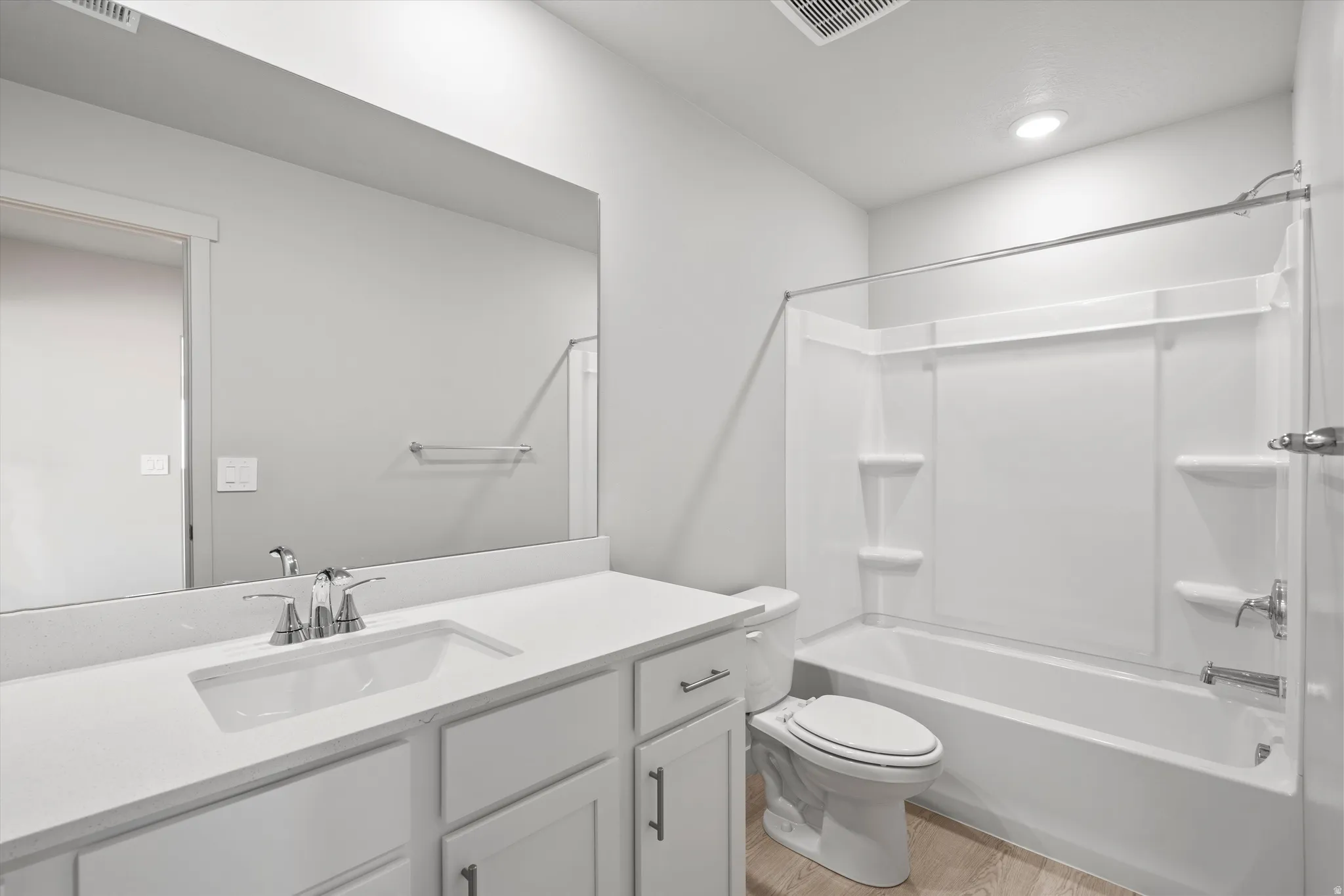 Vanity with an integrated sink, polished chrome faucet, and expansive mirror