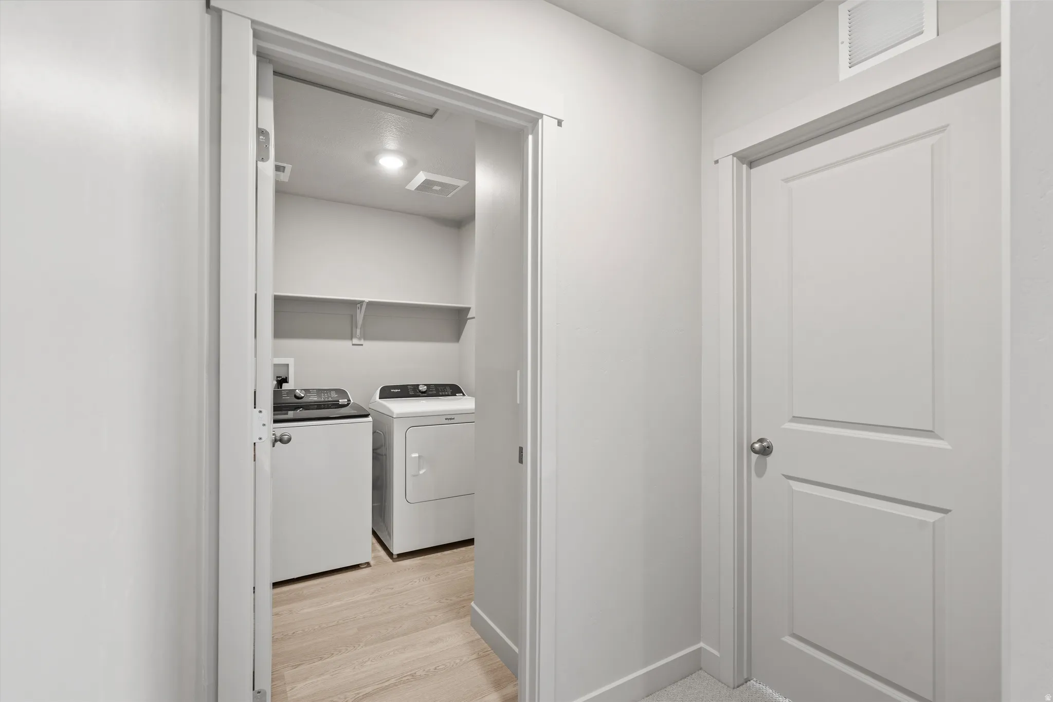 Laundry area featuring light wood-finish flooring, recessed lighting, and wall-mounted shelving