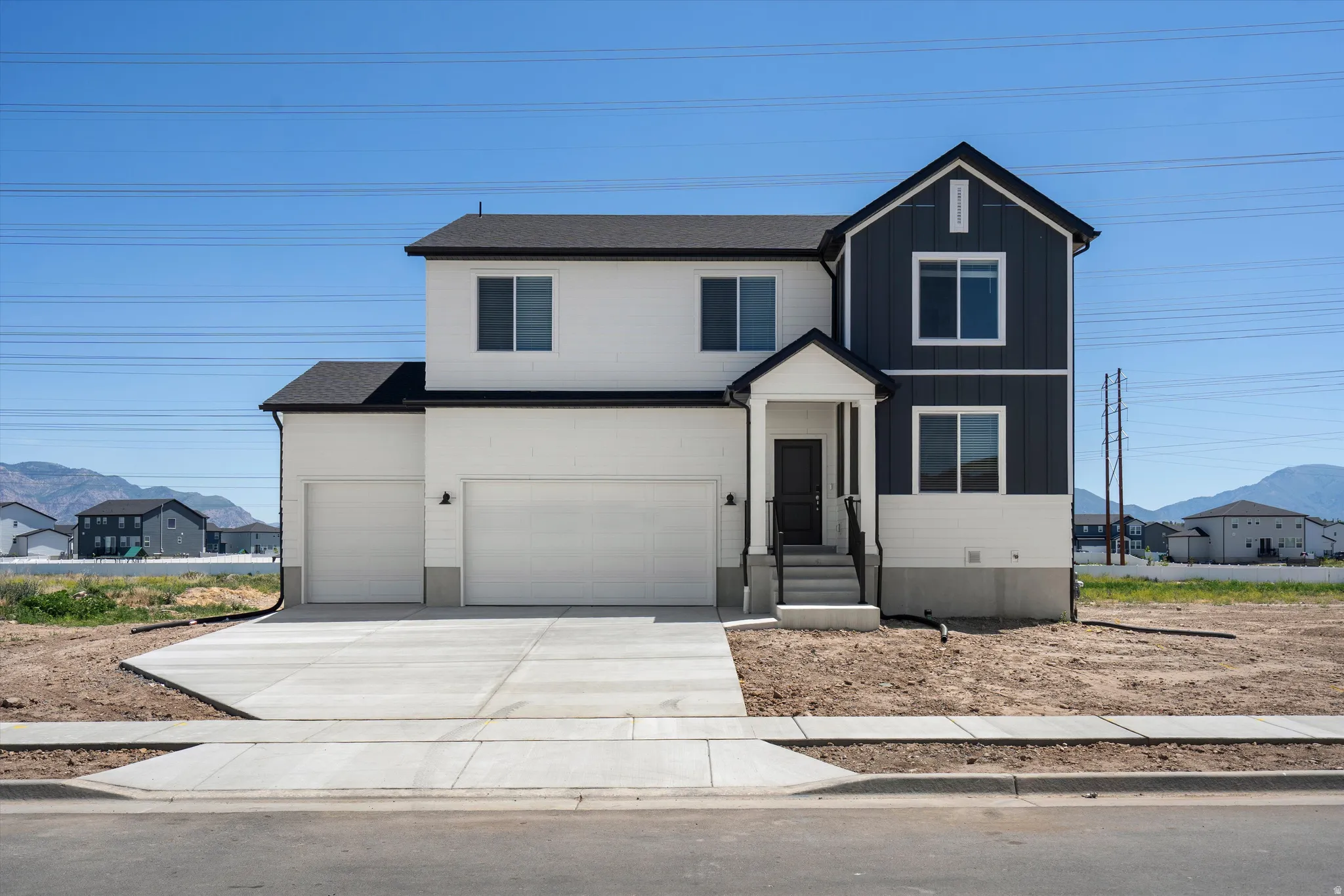 Two-story exterior with dark and light siding, covered entry, and attached two-car garage