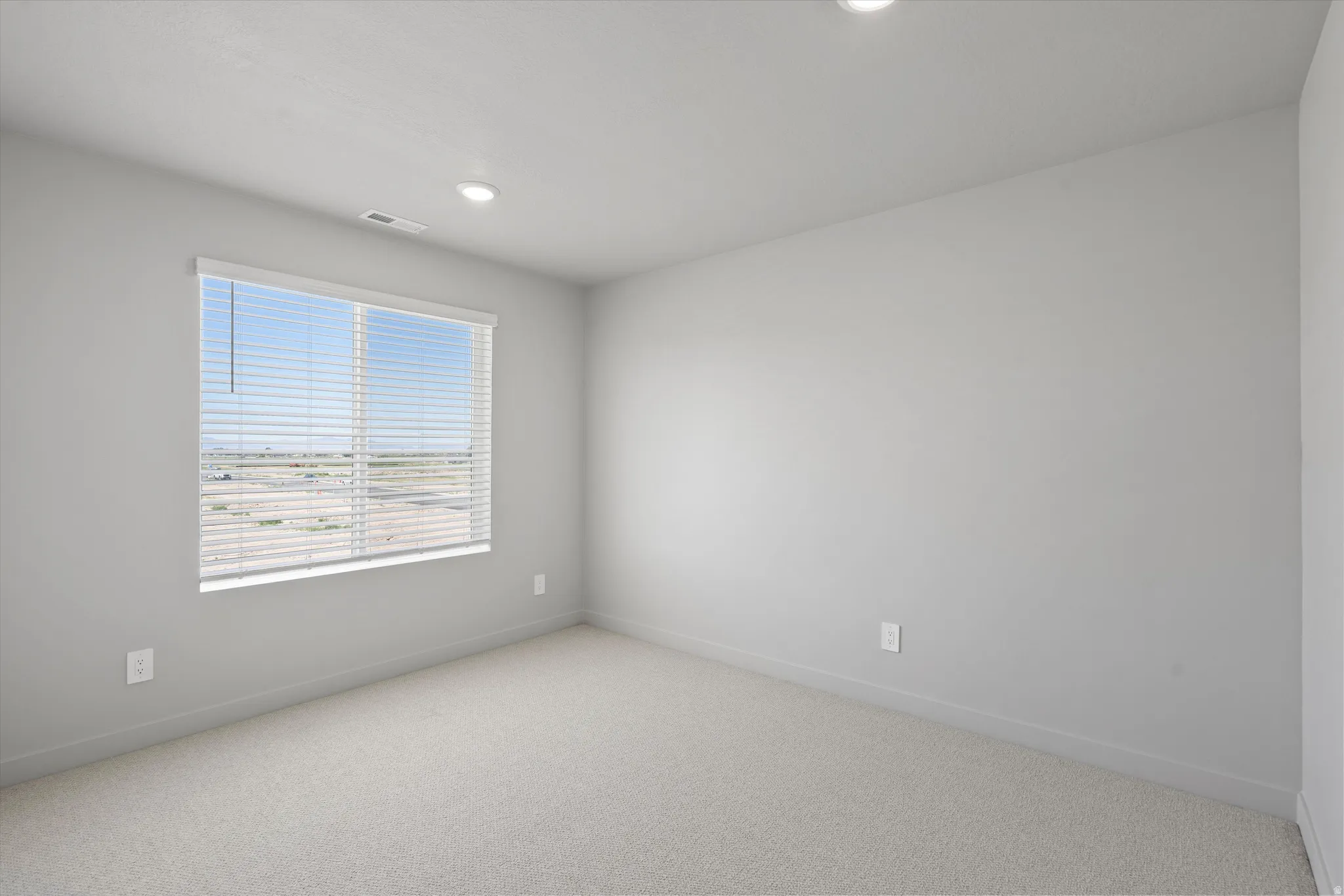 Wall-to-wall carpeting, recessed ceiling lights, and a window with horizontal blinds