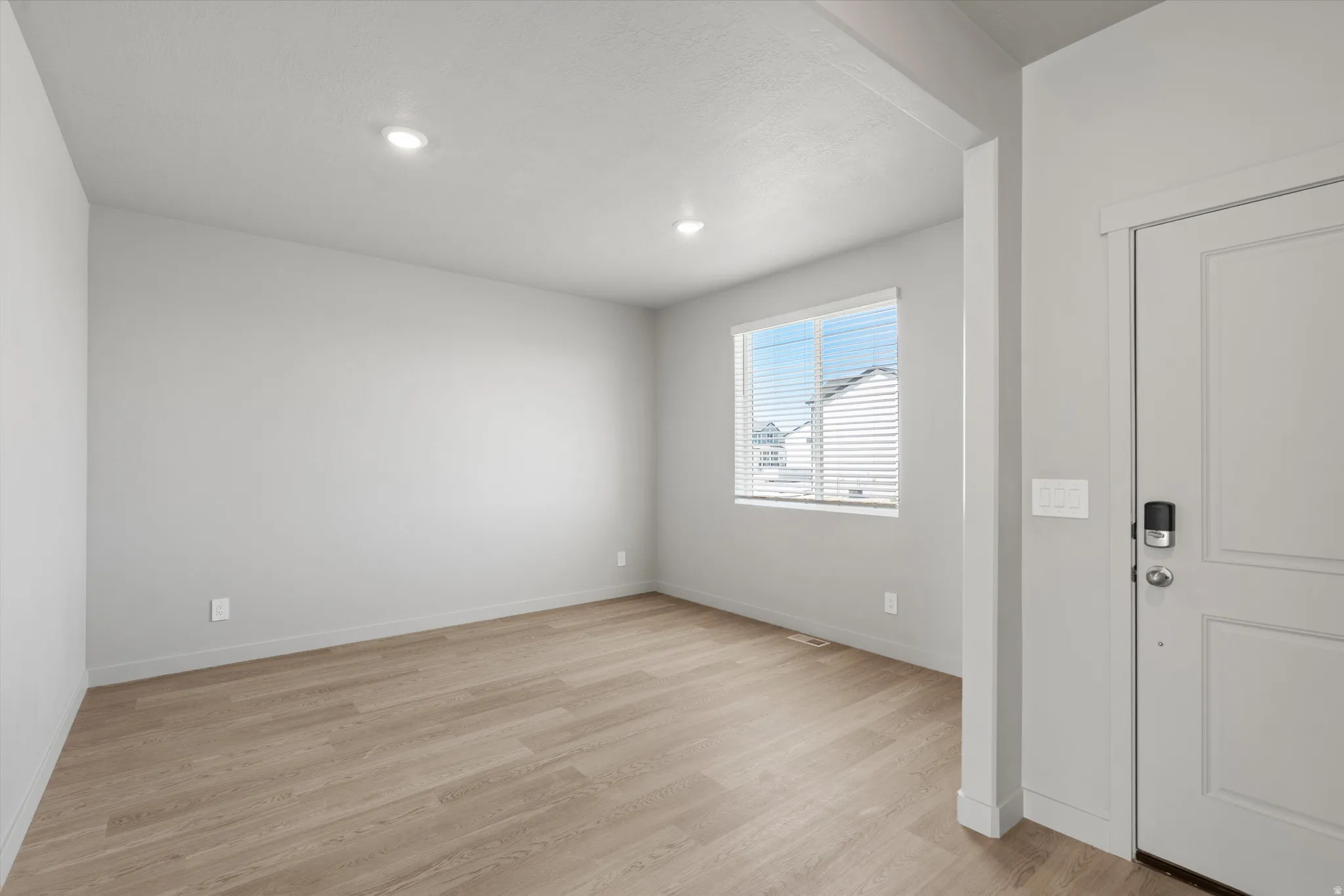 Recessed ceiling lighting, light wood-finish flooring, and a window with blinds