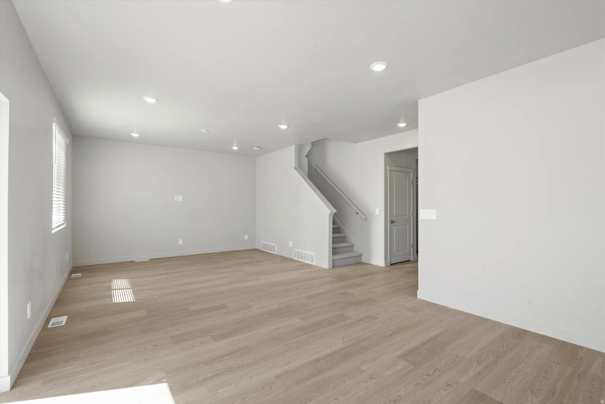 Expansive room featuring wood-finish flooring, recessed lighting, and a neutral wall color