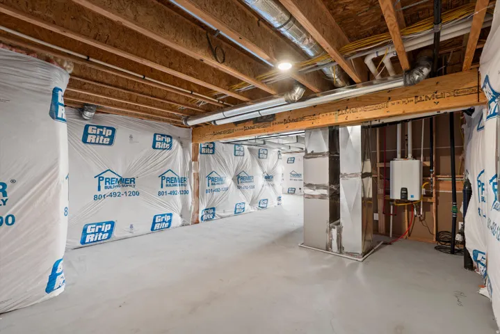 Unfinished lower level with exposed ceiling joists and ductwork, featuring a tankless water heater