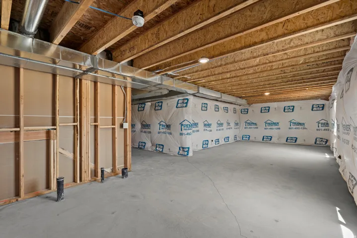 Unfinished concrete flooring with exposed wood joist ceiling, framed walls, and visible ductwork