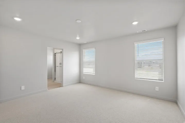 **DISCLIAMER** Some upgrades not photographed. Recessed lighting illuminates this carpeted room, featuring two windows with horizontal blinds and a doorway leading to an enclosed shower
