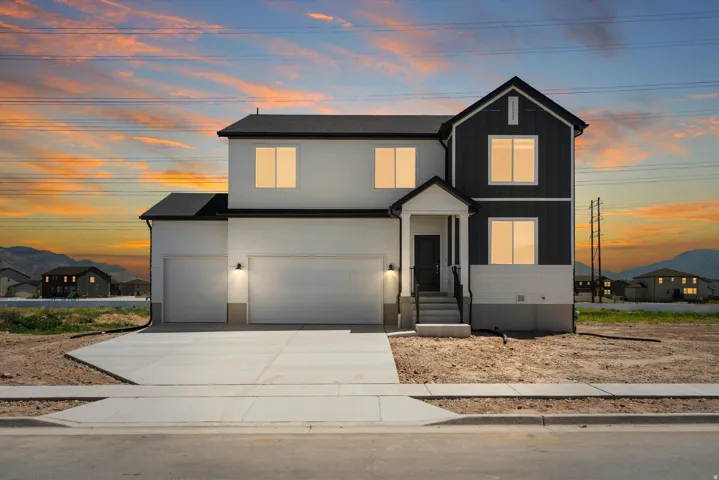 Two-story residence featuring a covered entry, attached three-car garage, and concrete driveway