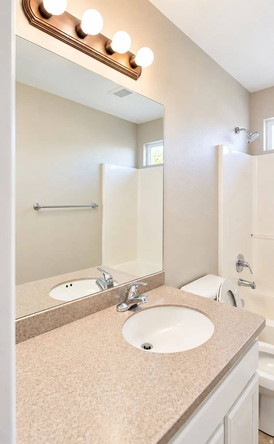 Guest bathroom featuring a vanity with an integrated sink, a large wall mirror, and a shower-tub combination with a chrome fixture