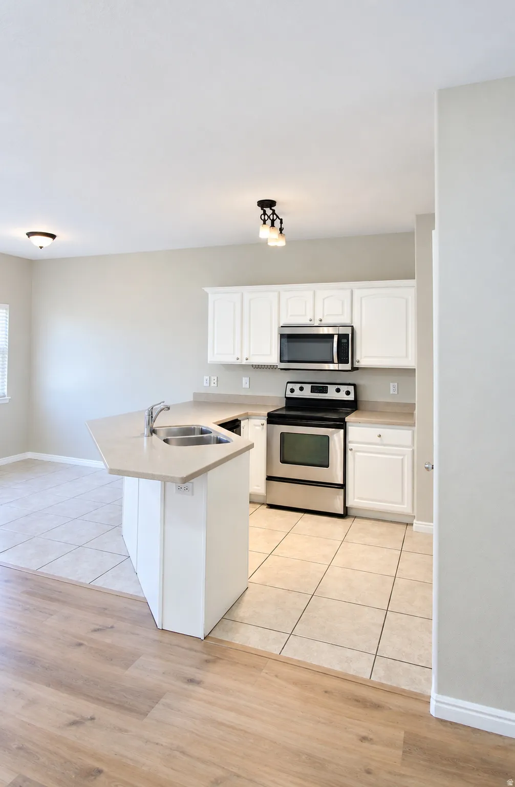 White cabinetry with stainless steel appliances, stone-finish countertops, and an integrated kitchen island with a double basin sink