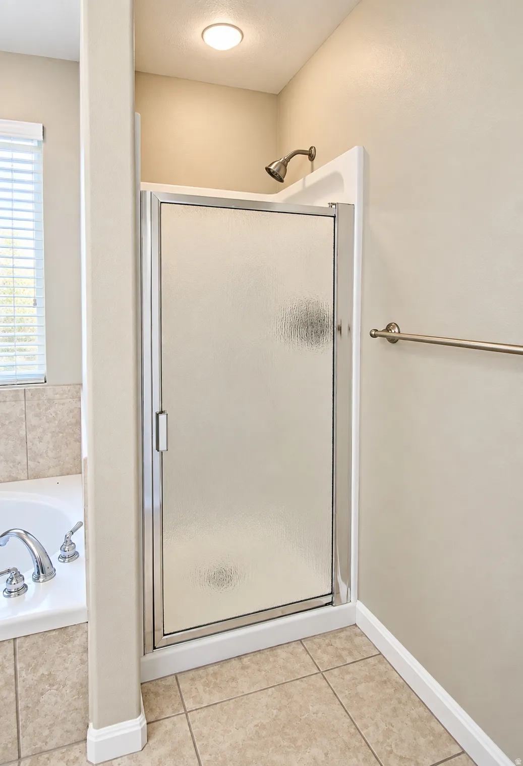 Enclosed shower with a frosted glass door, chrome shower head, and recessed lighting