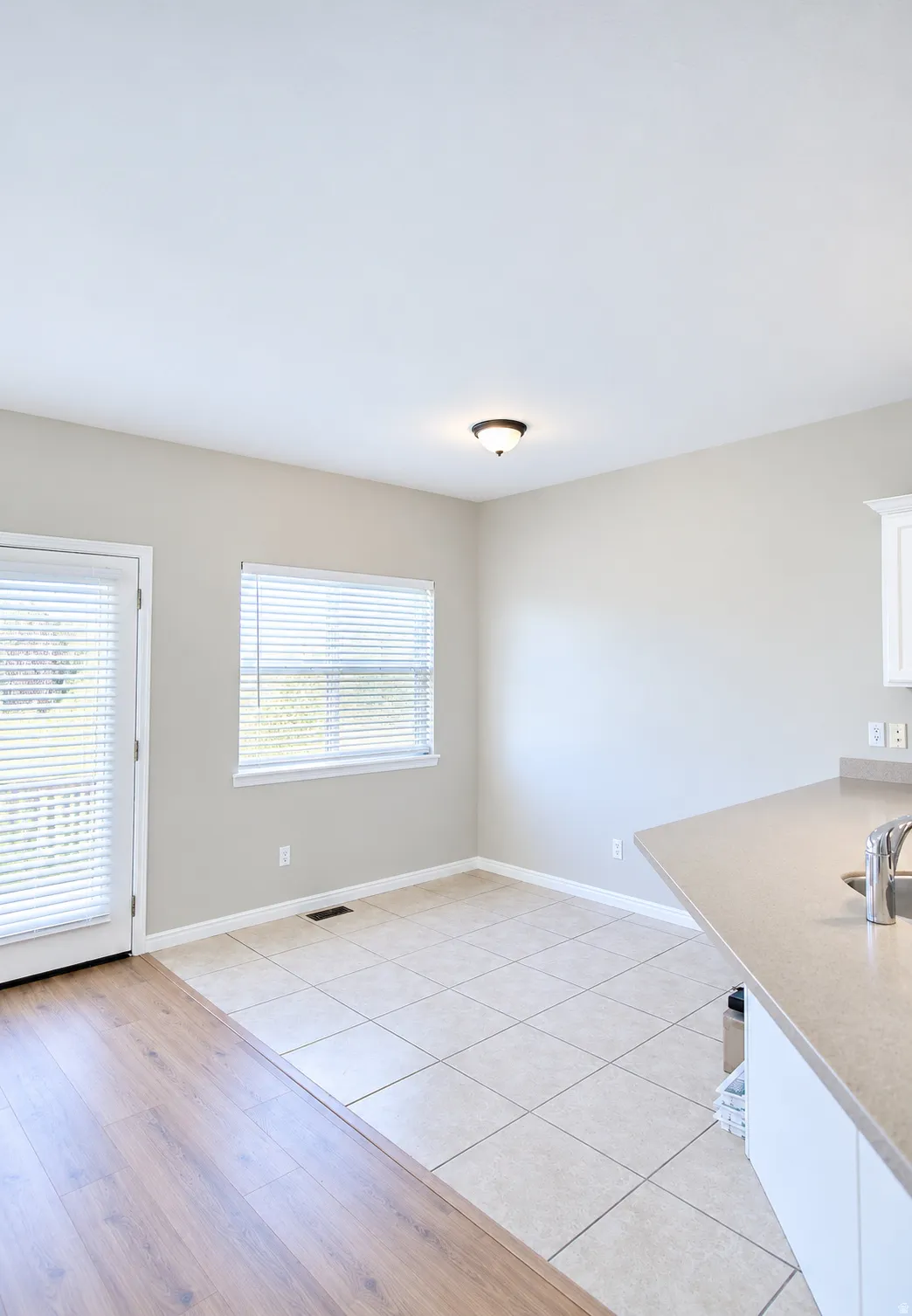 Tile flooring, wood-finish flooring, white cabinetry, integrated sink, and ceiling-mounted light fixture