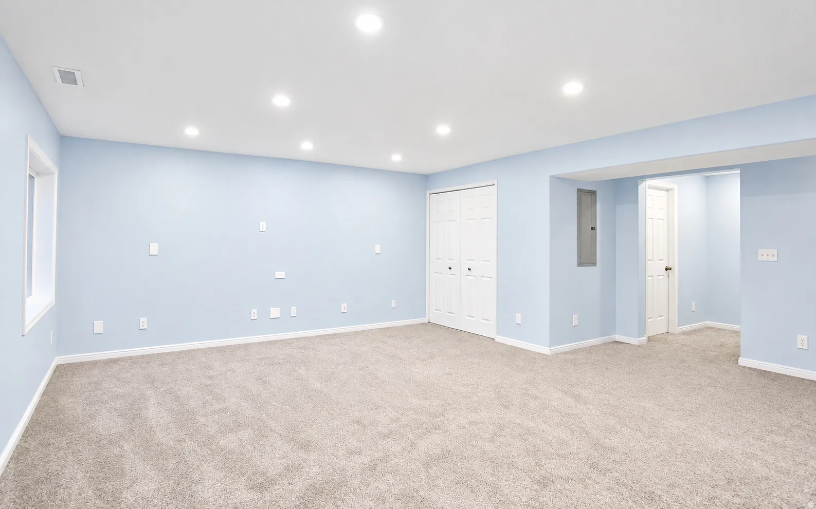 Spacious room with recessed lighting, light blue walls, and neutral carpeting