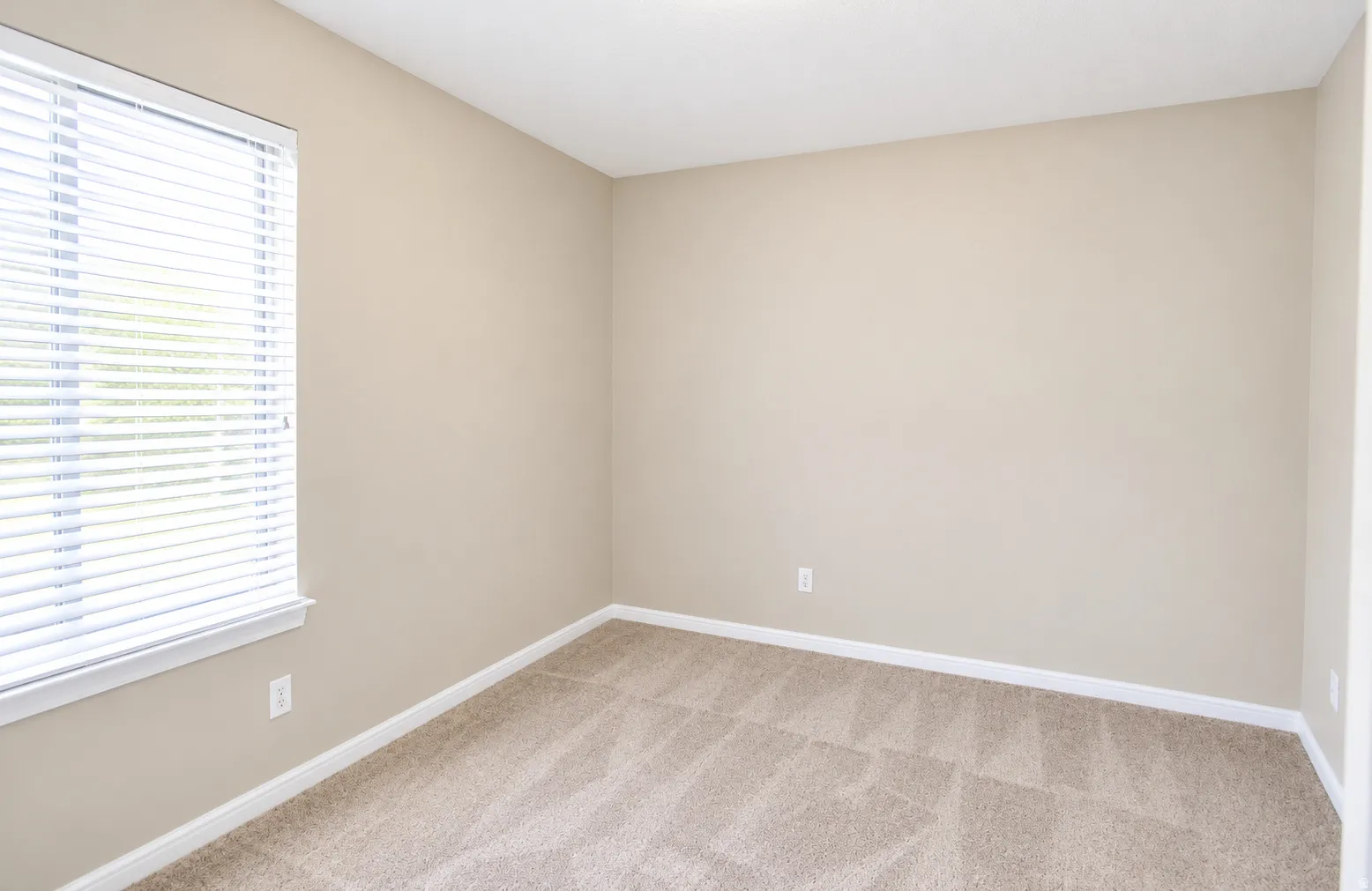Guest room featuring a single window with horizontal blinds and neutral-toned walls