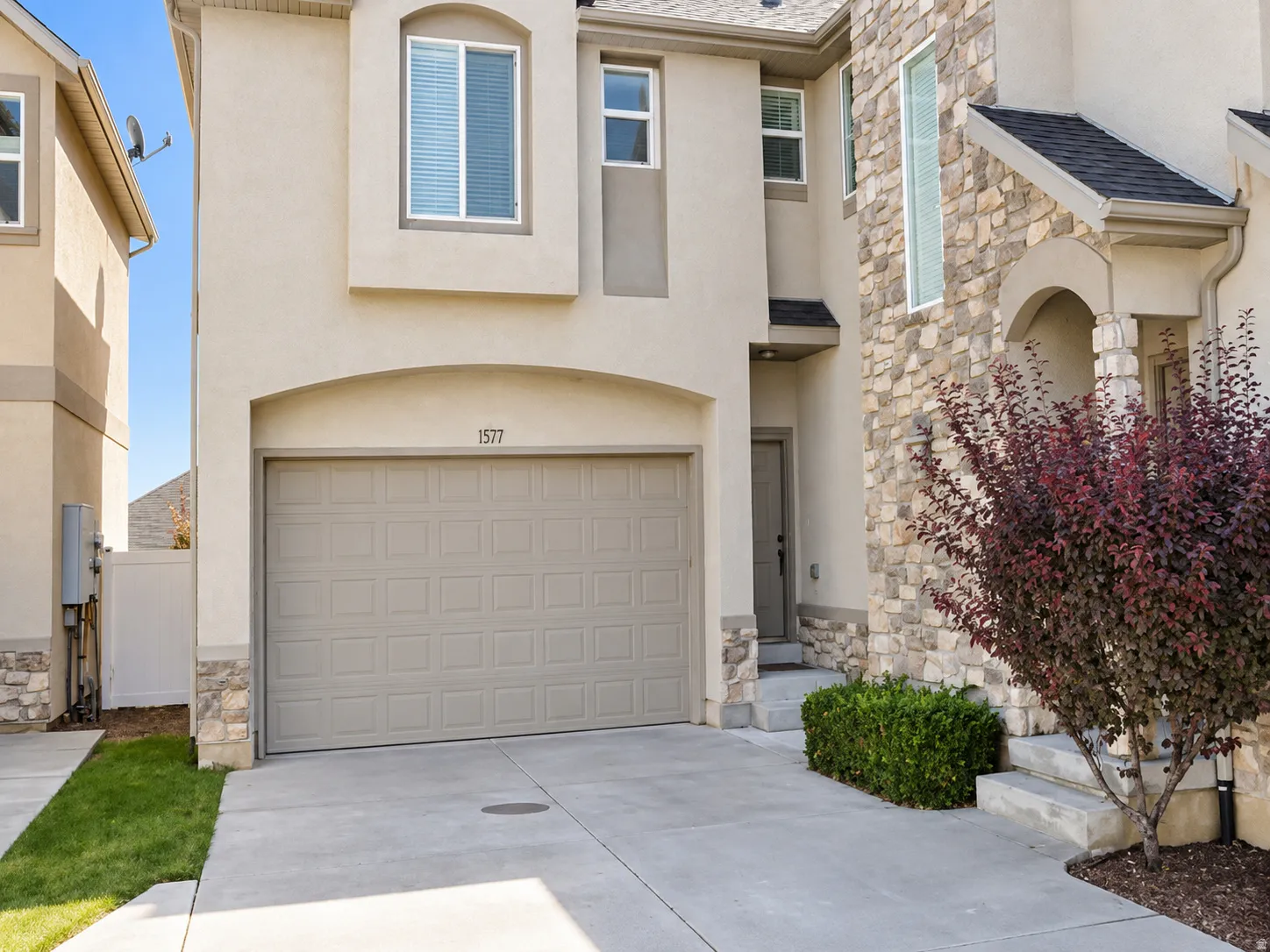 Multi-level facade featuring stone and stucco accents, an integrated single-car garage, and a covered entry