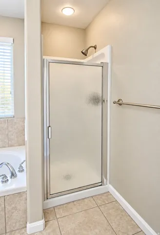 Enclosed shower with a frosted glass door, chrome shower head, and recessed lighting