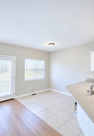 Tile flooring, wood-finish flooring, white cabinetry, integrated sink, and ceiling-mounted light fixture