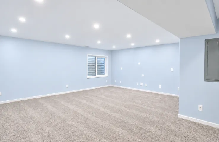 Recessed lighting, light blue wall paint, window with blinds, light-toned carpet, white trim