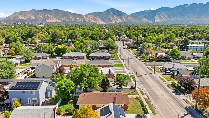 Residential neighborhood with mature trees, mountain backdrop, and solar panels