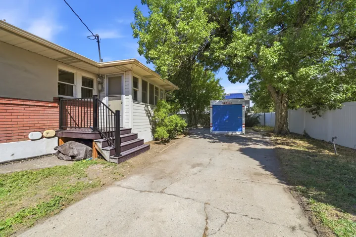 Exterior featuring a concrete driveway, mature trees, and a privacy fence