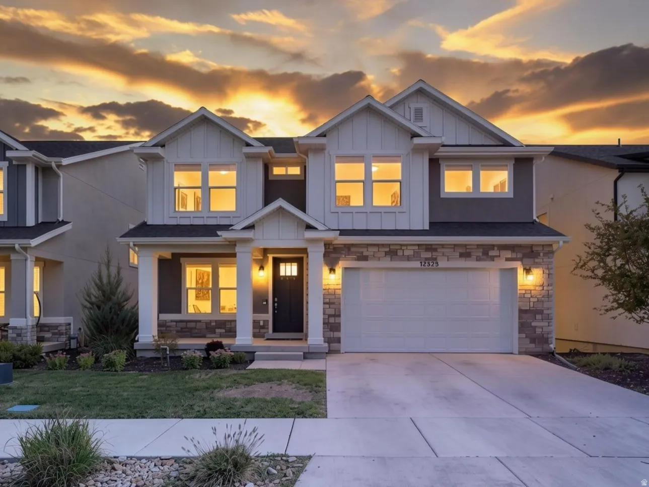 Modern craftsman-style exterior with stone and siding accents, prominent front entry, attached two-car garage, and concrete driveway